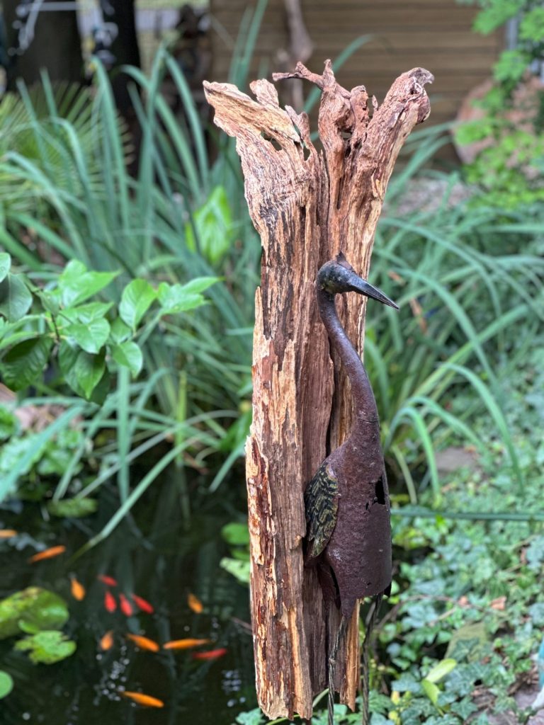 Stilvolle Metallskulptur eines Vogels vor einer Holzstruktur in einer modernen Galerie.